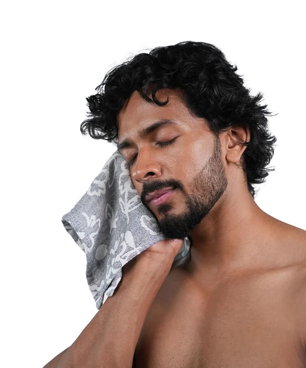 Man with a towel on his face against a white background